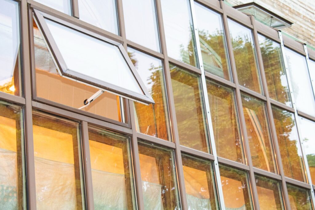 Modern aluminum double awning windows installed on a residential home, featuring durable frames and outward-opening glass panels for ventilation.