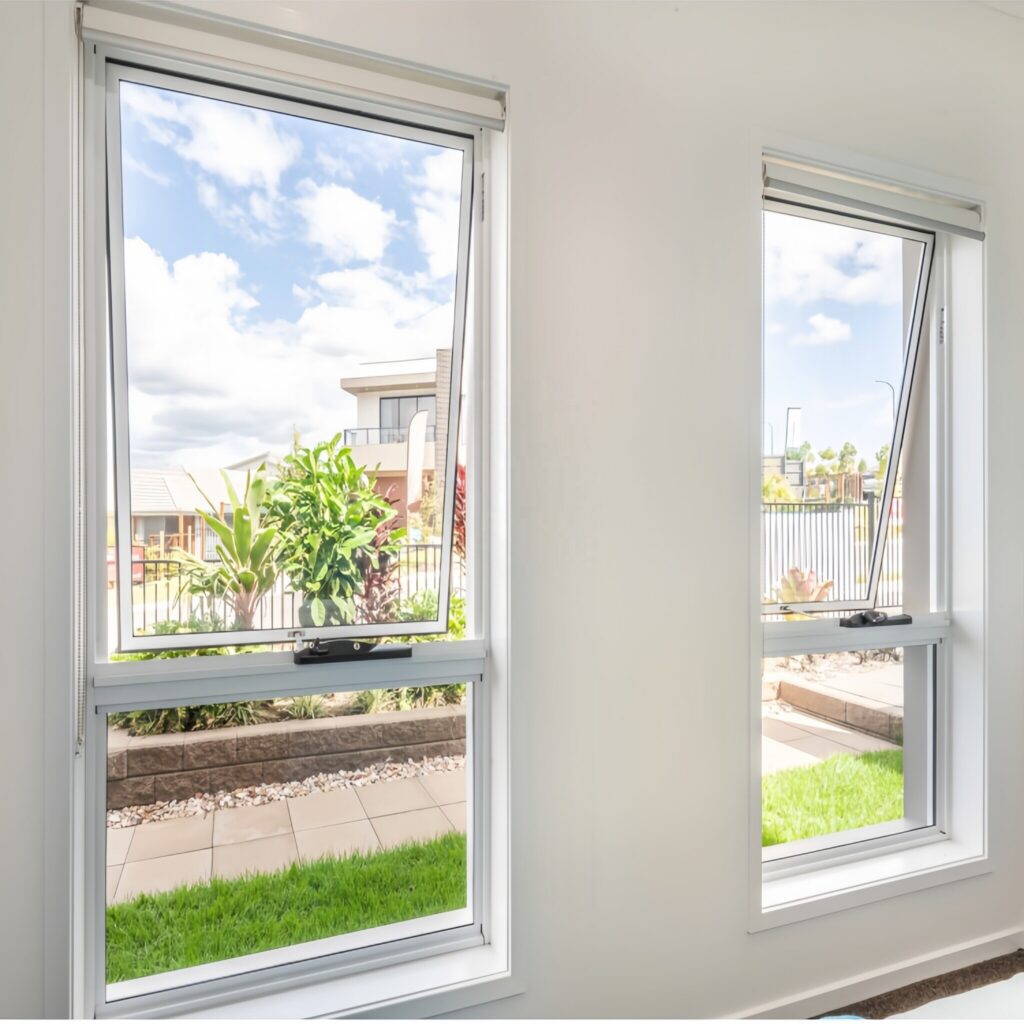 A house featuring newly installed, modern white aluminum storm windows that create a bold contrast against the traditional brickwork and white entryway trim.
