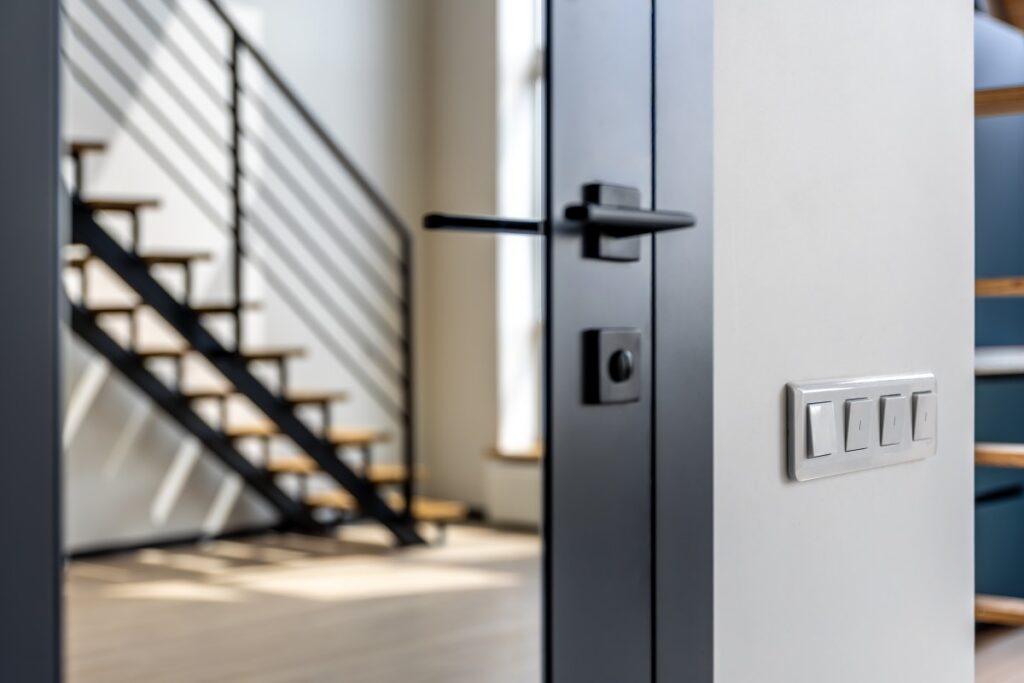 A close-up of a sleek, matte black aluminum door handle installed on a modern entry door by Nash Doors and Windows.