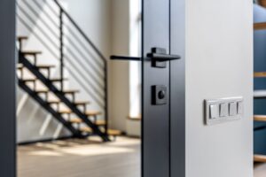 A close-up of a sleek, matte black aluminum door handle installed on a modern entry door by Nash Doors and Windows.
